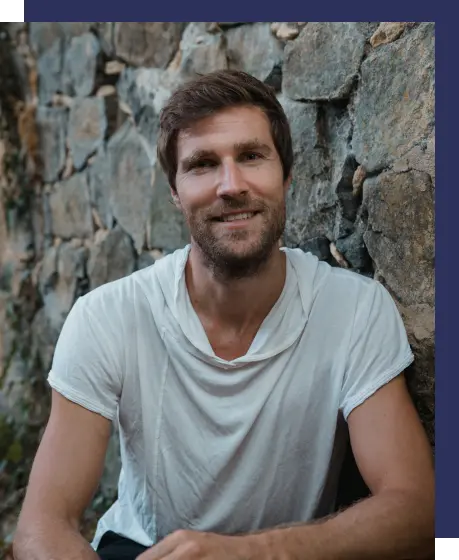 Andreas lächelnd vor Steinwand posierend